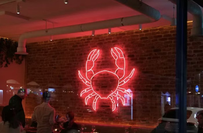 Salle de restaurant intime, mur de brique et enseigne néon en forme de crabe